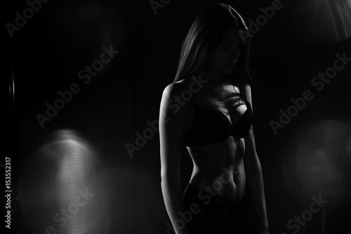 Black and white silhouette photo of a young girl in black lingerie and face in shadow.