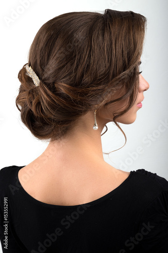 Assembled formal hairstyle dark hair decorated with a crest in the form of sheets, view profile