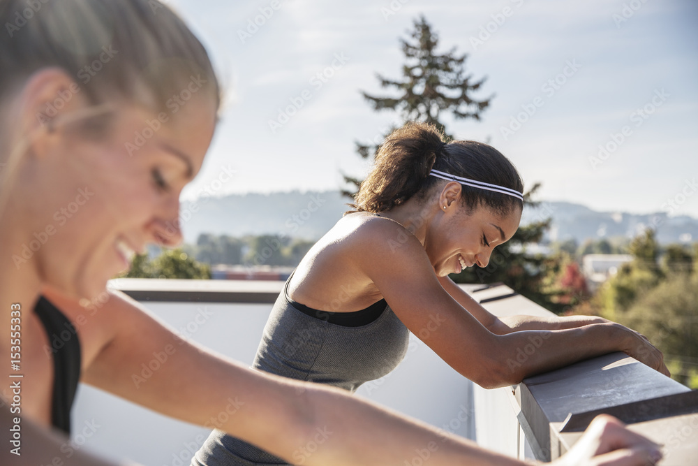 Friends exercising while leaning on railing at building terrace Friends exercising while leaning on railing at building terrace