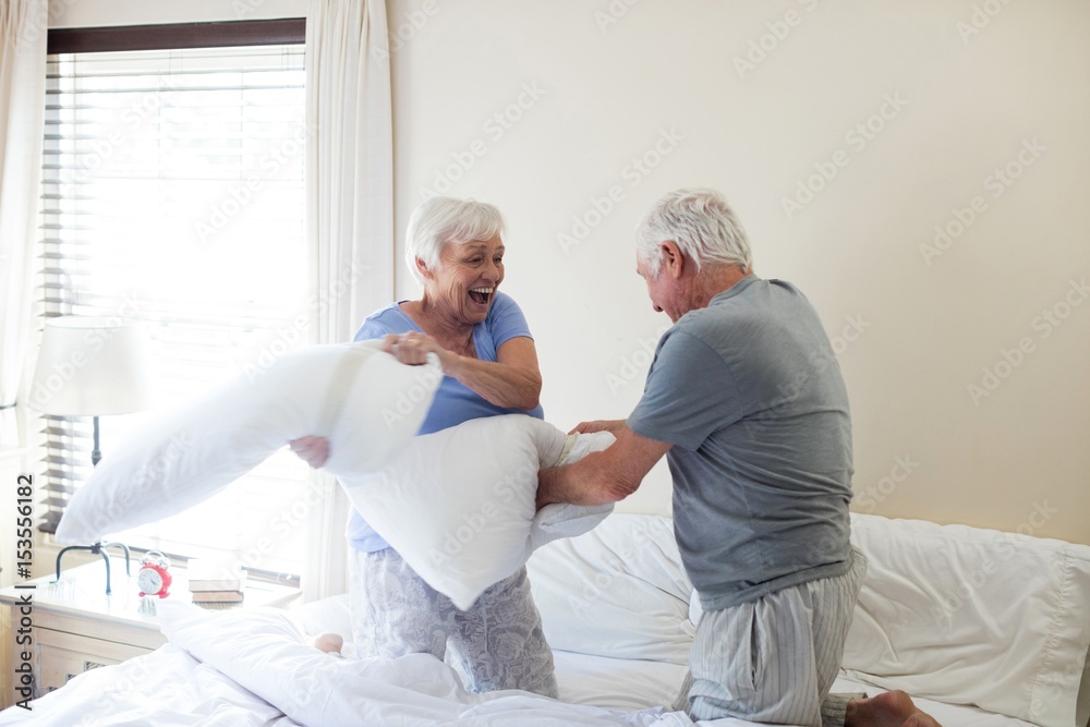 Fototapeta premium Senior couple having pillow fight on bed
