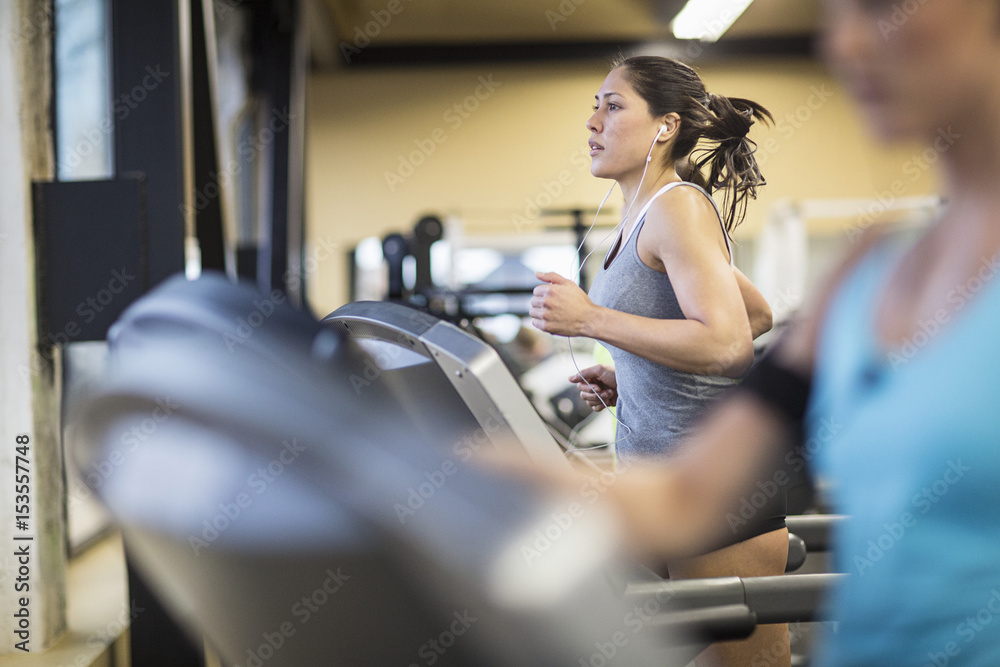 Women exercising on treadmills in health club Women exercising on treadmills in health club