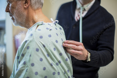 Midsection of male doctor listening to patient's breathing in hospital ward