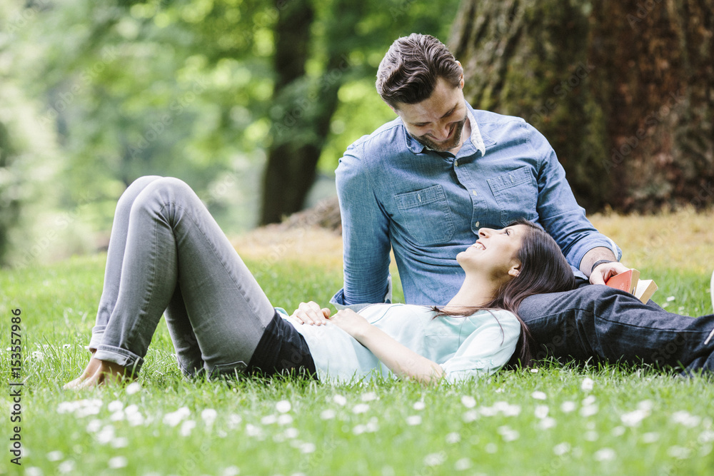 Happy girlfriend lying on boyfriend's lap in park Happy girlfriend lying on boyfriend's lap in park