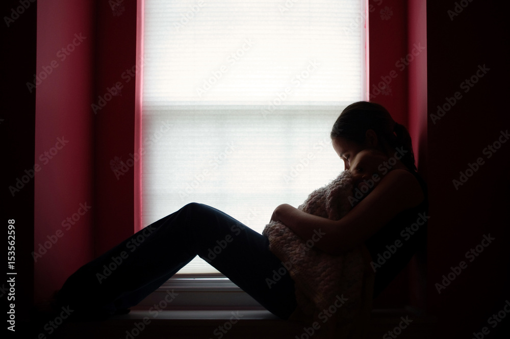 Mother with daughter relaxing by window at home Mother with daughter relaxing by window at home