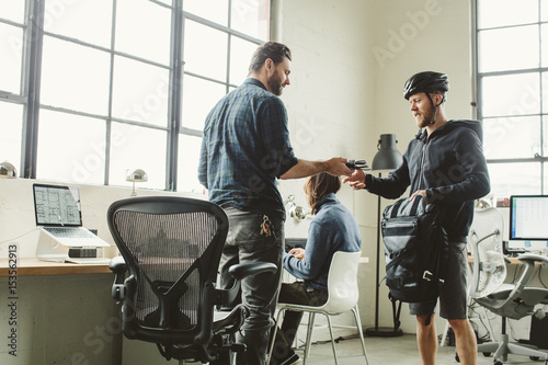 Businessman giving equipment to colleague in creative office