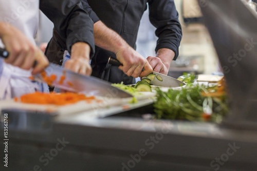 Midsection of chefs chopping vegetables at restaurant kitchen photo