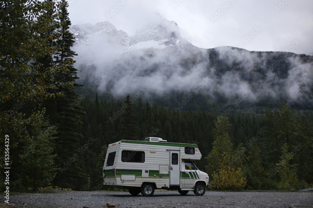 Motor home on road against trees and mountain during foggy weather Motor home on road against trees and mountain during foggy weather