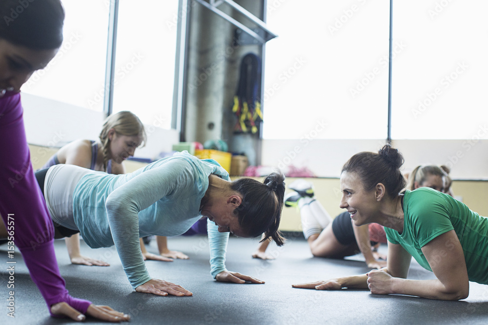 Instructor motivating woman doing push-ups at gym Instructor motivating woman doing push-ups at gym