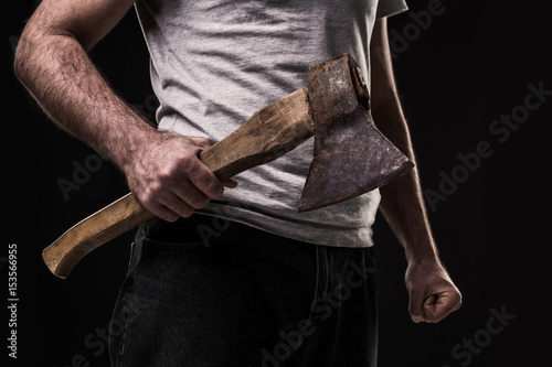 A man holds an ax in his hands against on black background