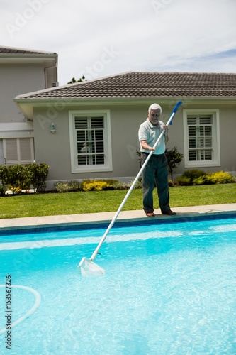 Senior man cleaning swimming pool