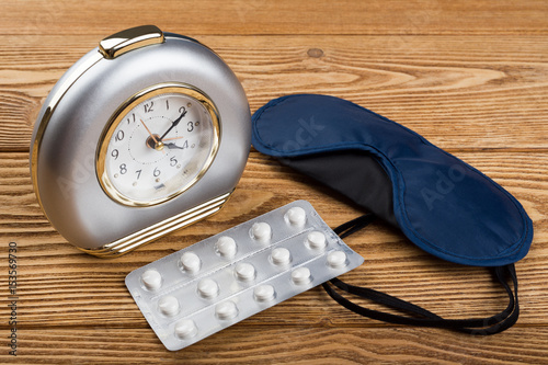 Quadro su tela Alarm clock, mask and sleeping pills on a wooden background