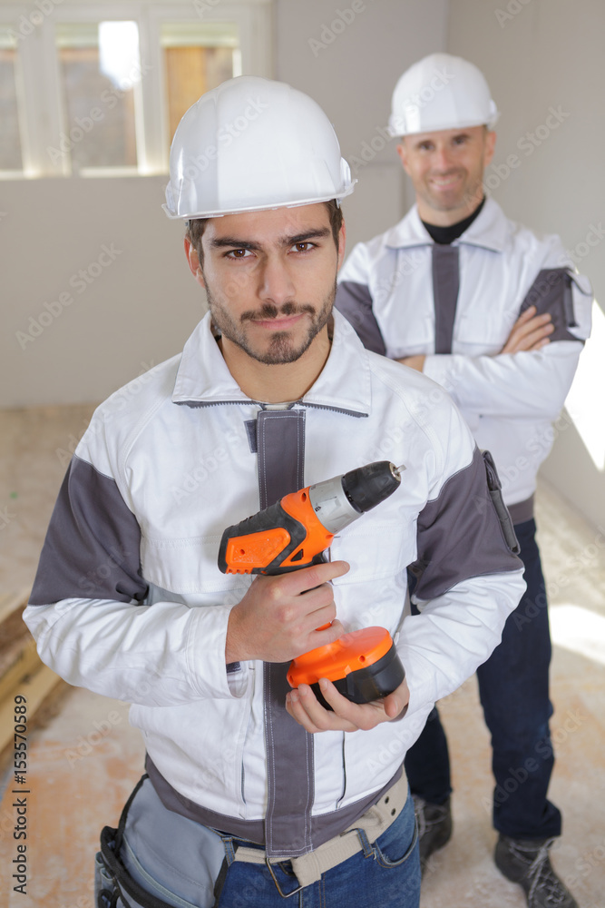portrait of a smiling young worker with drill portrait of a smiling young worker with drill
