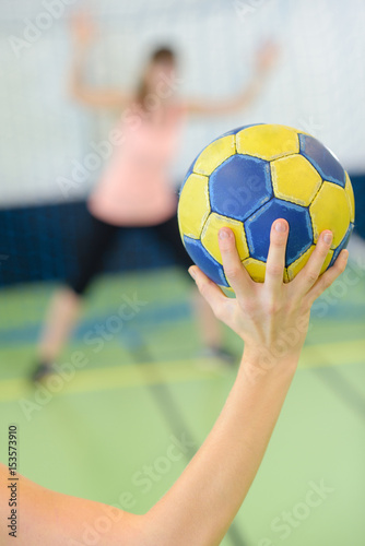 sportsman holding a ball against handball goal