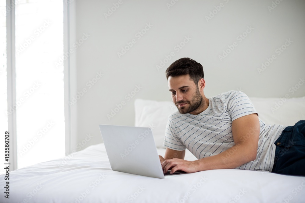 Man using laptop on bed Man using laptop on bed