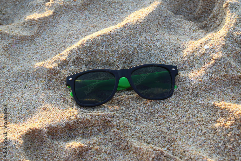 Travel to island Phuket, Thailand. The sunglasses on the sand in the sunny weather.
