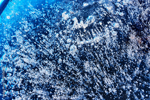 Frozen gas bubbles settle on the air cavity in the ice. A beautiful natural phenomenon. Greenhouse effect. Colorful blue cool colors. Abstract background. Frozen, unique ice bubbles..