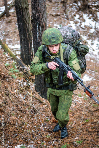 The army unit of Russian soldiers makes a march-throw through the coniferous forest, with weapons and full uniforms