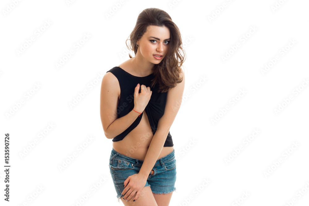 young beautiful girl in denim shorts lifts a hand t-shirt and looking directly young beautiful girl in denim shorts lifts a hand t-shirt and looking directly