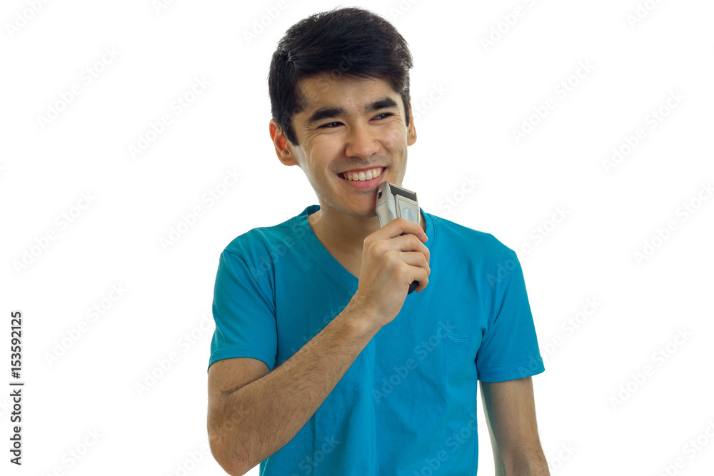 handsome young guy with black hair shaves the beard trimmer and laughs handsome young guy with black hair shaves the beard trimmer and laughs