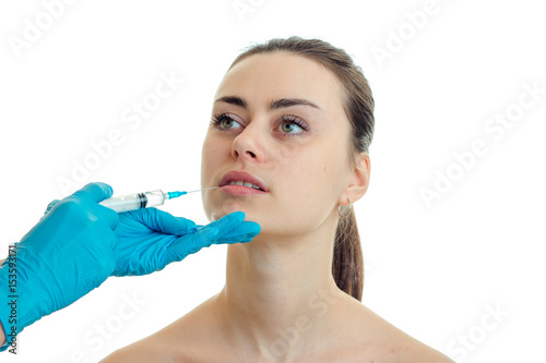 surgeon in blue gloves makes an analgesic injection in the face of a young girl close-up