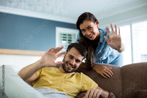 Portrait of couple waving hands in the living room