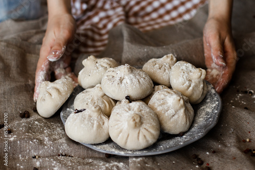 National Georgian cuisine Khinkali. Senior woman prepares khinkali. Top view raw meat dough dish uncooked. Process cooking.