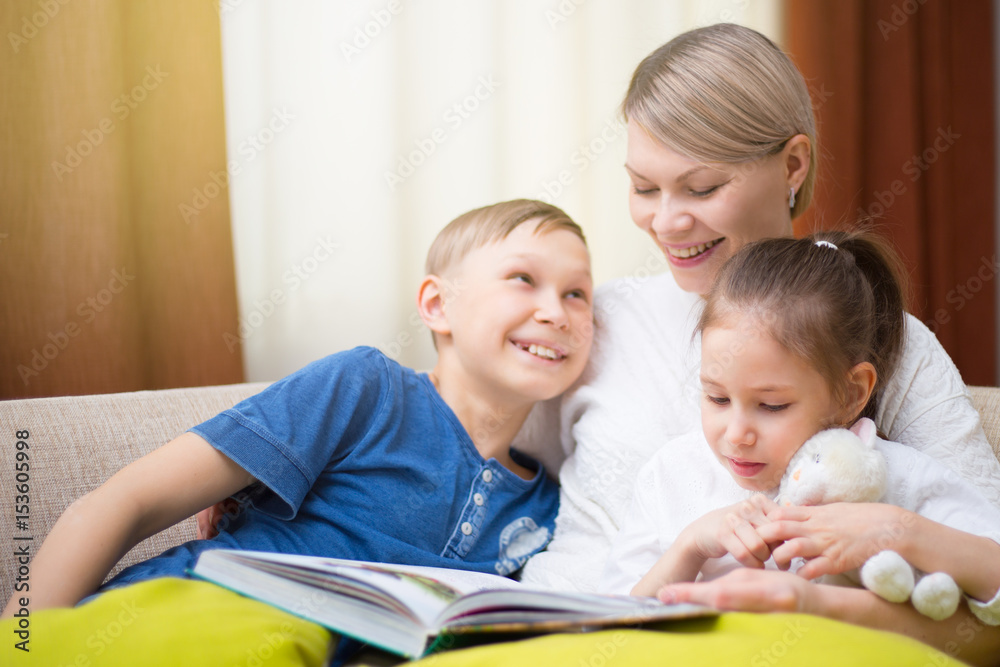 Beautiful mother is reading a book to her young children. Sister and brother is listening to a story. Beautiful mother is reading a book to her young children. Sister and brother is listening to a story.