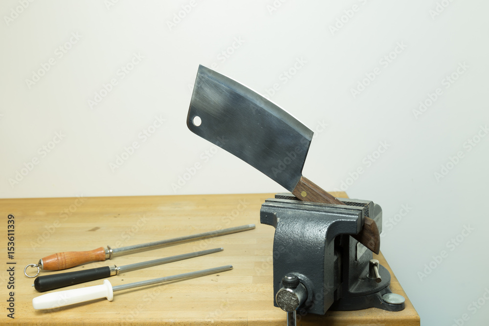 Cleaver pressed by a vise with sharpening steels on the side Stock