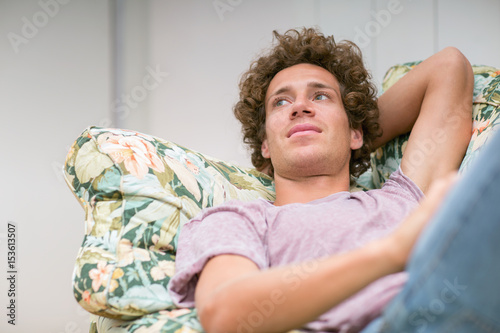 Young man relaxing on sofa daydreaming photo