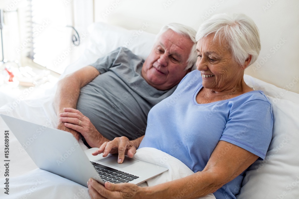 Senior couple using laptop in the bedroom Senior couple using laptop in the bedroom