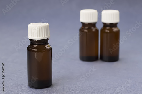 Three dark glass bottles on a grey background.