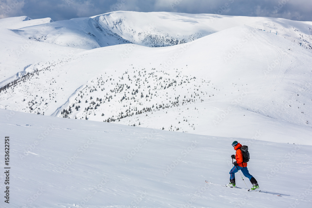 A skier is climbing the mountain ridge, snow, sunny day, in Carpathian mountains, skitouring in Ukraine.