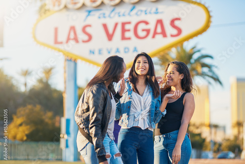 group of girls on vacation having fun together in front of welcome to las vegas sign