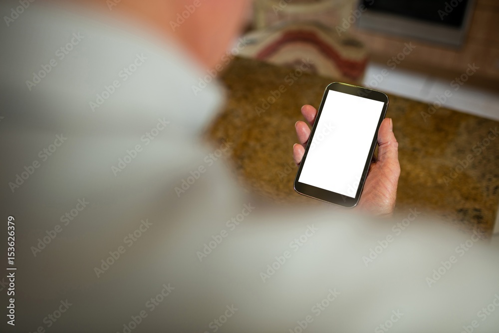 Obraz premium Senior man holding mobile phone in the ktchen