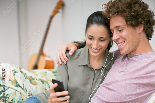 Couple listening to music from mobile phone on sofa photo