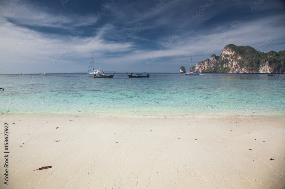 KO PHI PHI, THAILAND, February 1, 2014: Tropical beach with traditional long tail boats on the beach of Ko Phi Phi, Andaman Sea, famous tourist destination in Thailand KO PHI PHI, THAILAND, February 1, 2014: Tropical beach with traditional long tail boats on the beach of Ko Phi Phi, Andaman Sea, famous tourist destination in Thailand