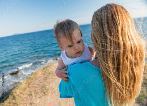 Young woman embracing little dougter at beach photo