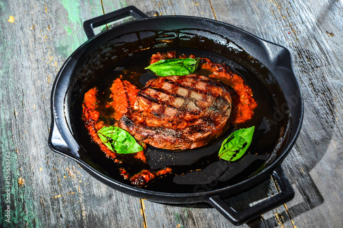 Grilled Steak on grill iron pan on wooden background