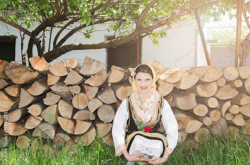 woman or girl in peasant clothes posing in front of cameras outside photo