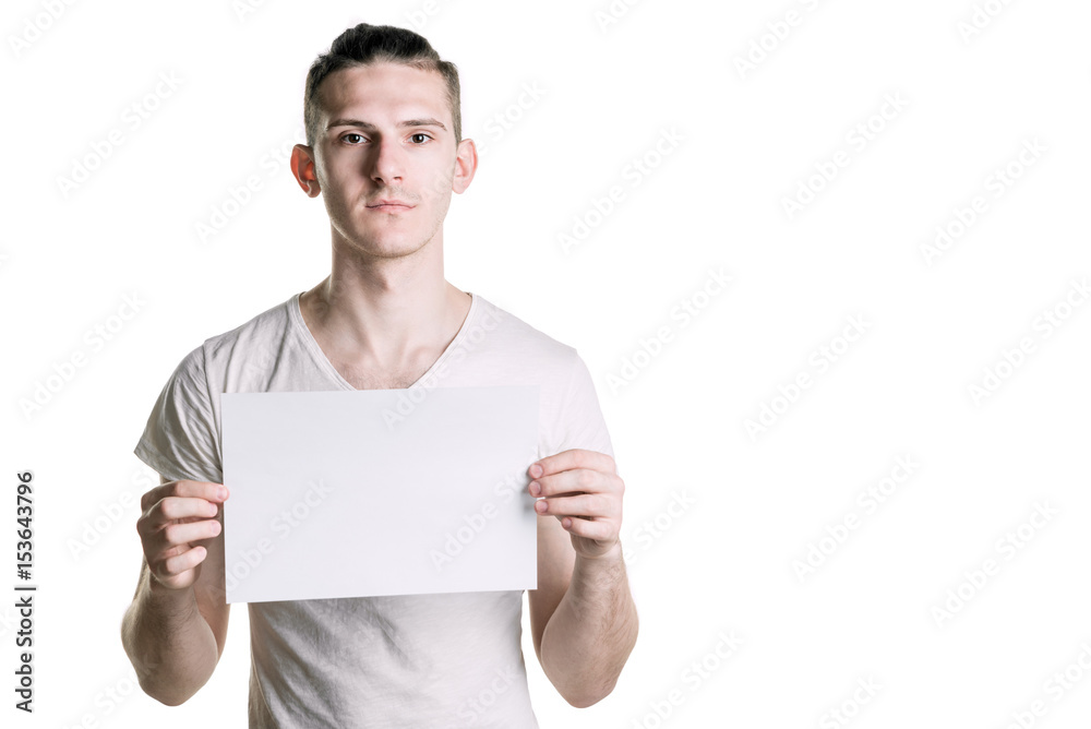 Young handsome guy with a blank sheet of paper, seriously looking at the frame. Place for signature, text. Horizontal frame Young handsome guy with a blank sheet of paper, seriously looking at the frame. Place for signature, text. Horizontal frame