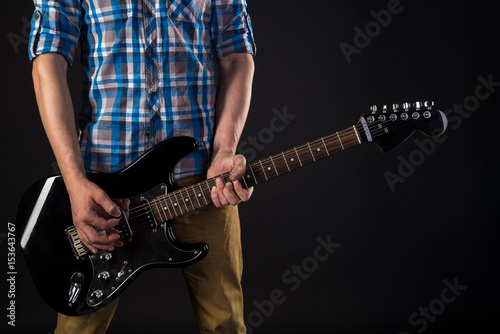 Music and art. The guitarist holds an electric guitar in his hands, on a black isolated background. Playing guitar. Horizontal frame