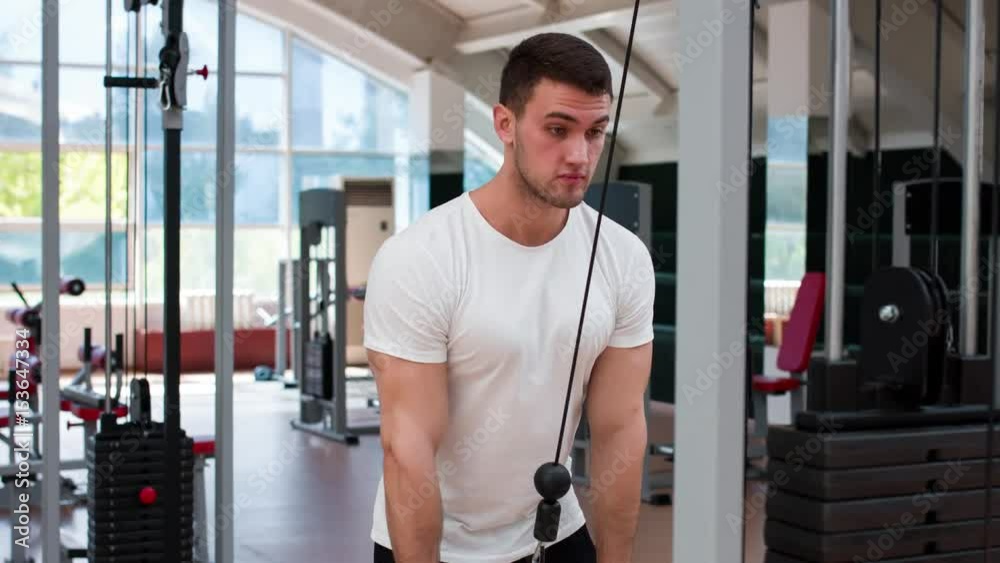 Muscular man working out in gym doing exercises at triceps. Muscular man working out in gym doing exercises at triceps.