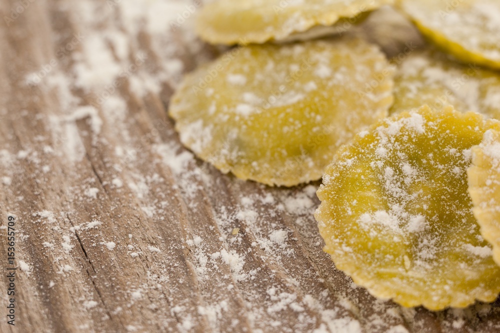 Round ravioli pasta dusted with floor on wooden background