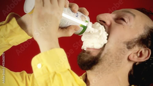 A funny ugly man spraying whipped cream directly into his mouth, feeling hungry, being glutton and greedy. Close-up shot.
 photo