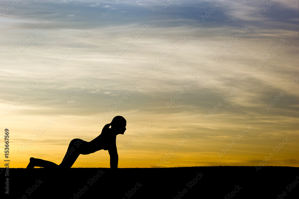 Woman practicing Cow yoga pose outdoors over sunset sky background.
