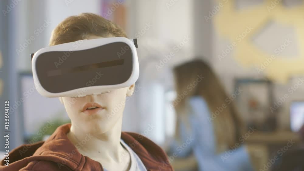 In a Computer Science Class Boy Wearing Virtual Reality Headset Works on a Programing Project. Shot on RED EPIC-W 8K Helium Cinema Camera. In a Computer Science Class Boy Wearing Virtual Reality Headset Works on a Programing Project. Shot on RED EPIC-W 8K Helium Cinema Camera.