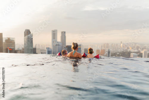 Photography Mother and her children enjoying the view from roof top swimming pool in Singapo