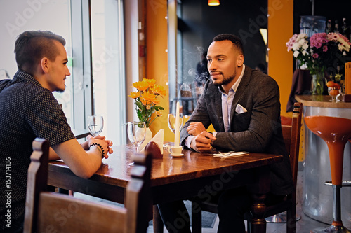 Two men talks and using a laptop in a restaurant.