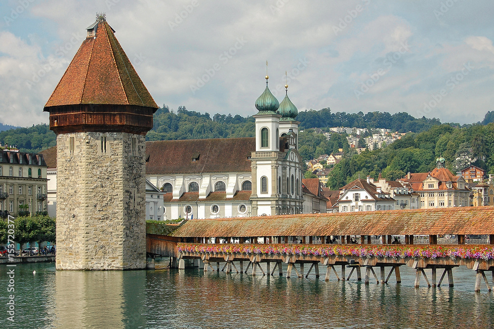 The wooden pedestrian Chapel Bridge over the Reuss River, the octagonal Water Tower and the Baroque Jesuit Church of Lucerne (Luzern), Switzerland