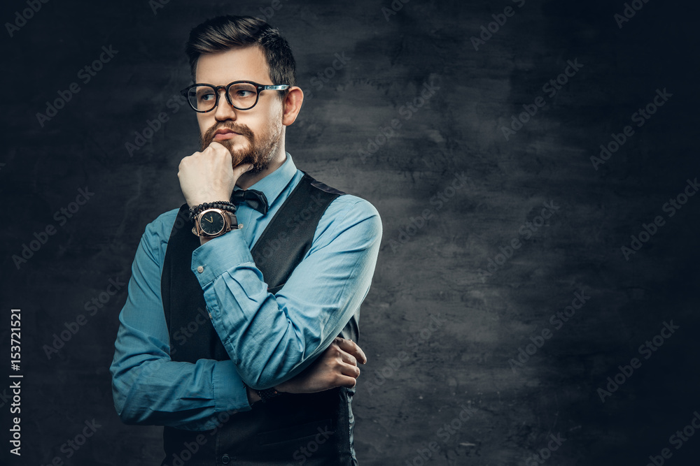 An elegant bearded hipster male dressed in a blue shirt and waistcoat.